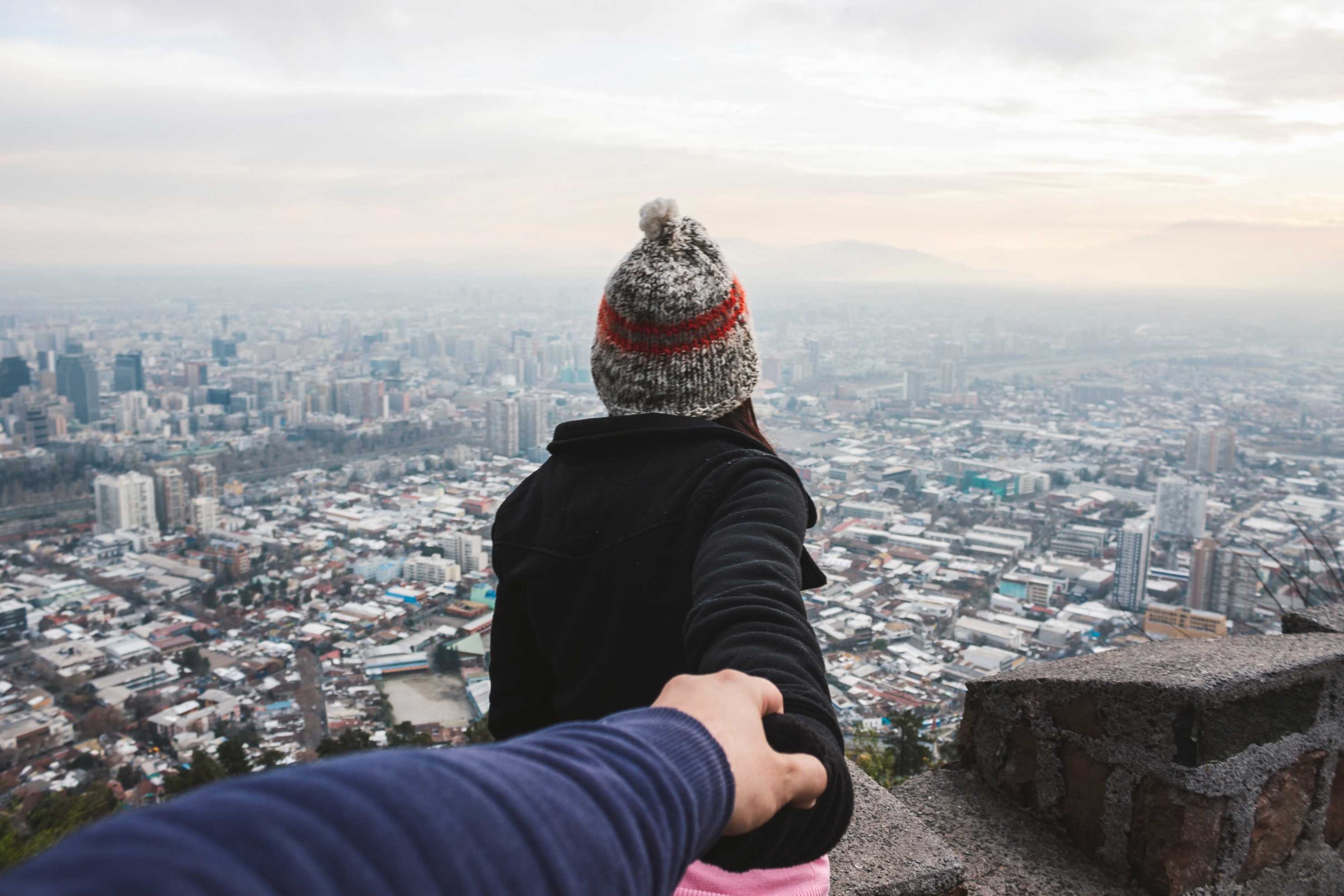 Woman leaning over building edge trusting partner to hold on
